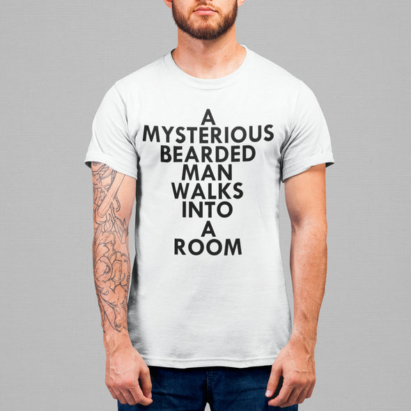 A MYSTERIOUS BEARDED MAN WALKS INTO A ROOM TSHIRT IN WHITE WHITE MAN STANDING.